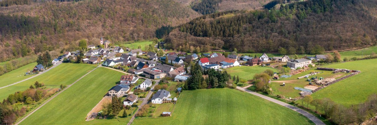 Luftaufnahme Kaltenborn Luftaufnahme Ort Kaltenborn mit Häusern und Straßen, umgeben von grünen Feldern und bewaldeten Hügeln. Der blaue Himmel ist teils bewölkt.