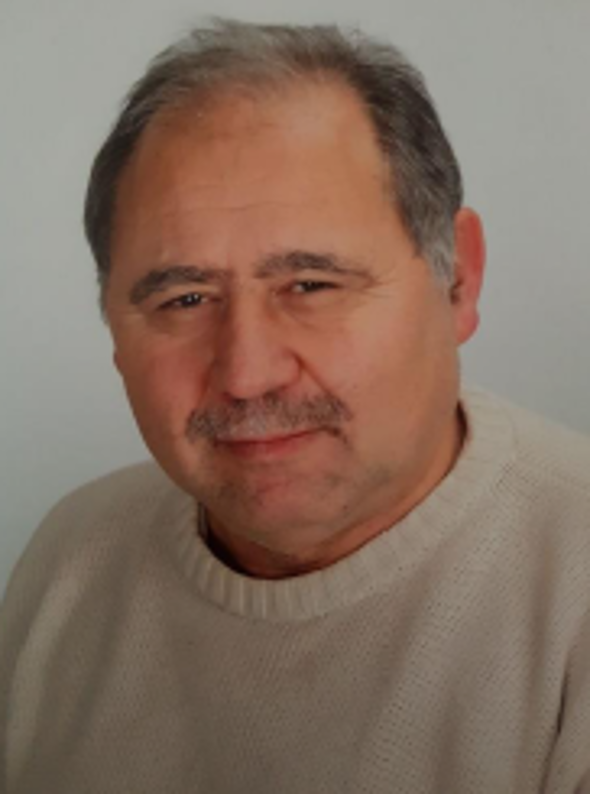 Porträt von Manfred Hoffmann, lächelnd vor neutralem Hintergrund