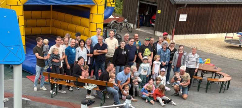 Gruppenfoto des Bürgervereins Kaltenborn. Es ist eine Ansammlung von Erwachsenen und Kinder zu sehen. Im Vordergrund ist ein Spielplatz, im Hintergrund eine Hüpfburg.